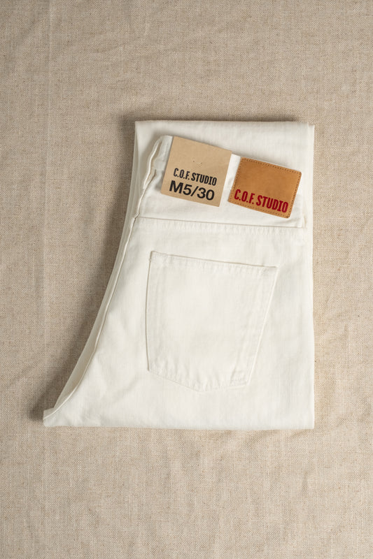White jeans with a brand label on a beige fabric background